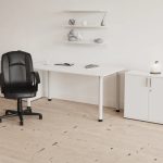 black leather office chair in front of white office desk room shot
