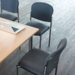 stackable conference chairs in black fabric and no arms around a meeting table