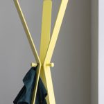 designer coat stand in yellow with coat hanging on it