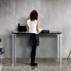 sit - stand desks. Lady standing at height adjustable desk