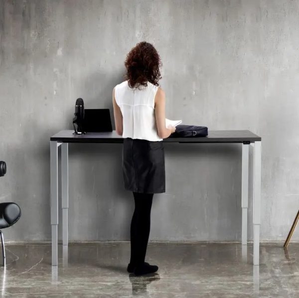 sit - stand desks. Lady standing at height adjustable desk
