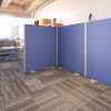 office screen in blue fabric floor standing. IN reception area with grey sofa and coffee table
