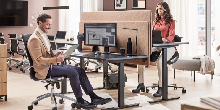 lady and man sat at height adjustable desk in modern office