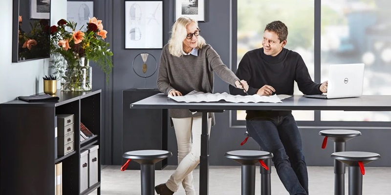 Create a productive workspace image of a couple in a meeting room at height adjustable desk