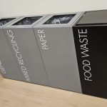 Recycling bin for offices in a row black and grey with white lettering. Office recycling bins
