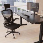 executive mesh chair behind a black height adjustable desk in office with city view