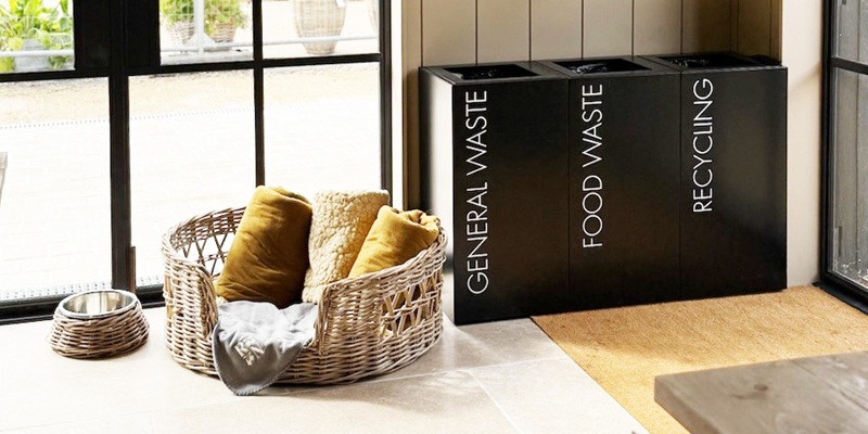 contemporary recycling bin black with white lettering in a row in cafe setting with dog basket by the side