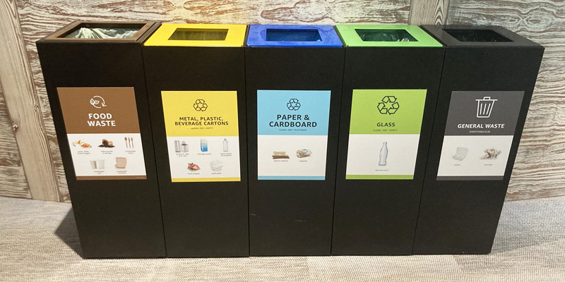 office recycling bins with coloured recycling bin tops in a row with waste stream labelling