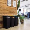 Black office recycling bins with grey, orange and blue tops for different waste