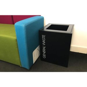short black office recycling bin by side of sofa.