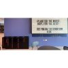 row of stylish office recycling bins black with ink lettering by purple wall with big lightbox
