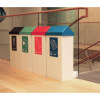 row of 4 office recycling bins by stairs with different coloured swing tops and labels to indicate waste stream