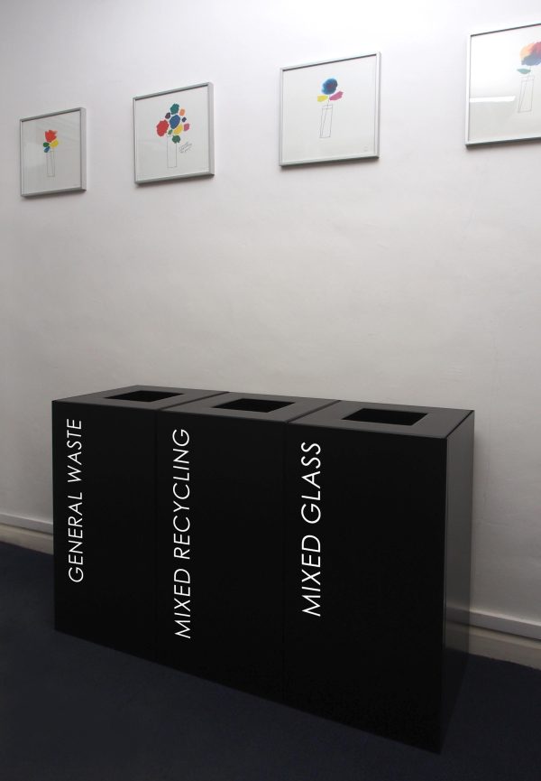 row of 3 black office recycling bins with white lettering.