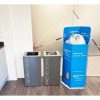 2 silver office recycling bins with white lettering Gneral Waste and Mixed Recycling. Next to blue charity donations bin