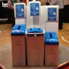 3 office recycling bins with blue tops and signage for Confidential paper