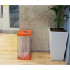 transparent office recycling bin with orange top and base in reception area and plant