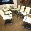 glass meeting table with chrome frame surrounded by cream leather meeting chairs