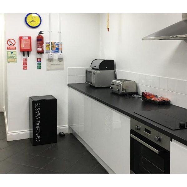 office recycling bin in kitchen . Black with white lettering General Waste