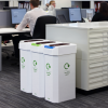 office scene with 3 cardboard office recycling bins at end of office storage with people in background